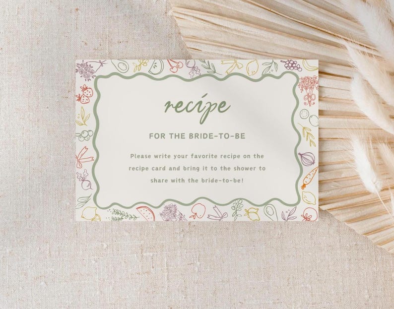 May include: A white card with a green border and a green wavy line around the text. The card has a hand-drawn illustration of vegetables and fruits around the border. The text on the card reads "recipe" in a green font and "FOR THE BRIDE-TO-BE" in a brown font. The text below reads "Please write your favourite recipe on the recipe card and bring it to the shower to share with the bride-to-be!"
