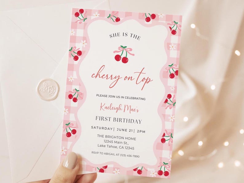 Cherry Birthday Invitation includes pink and white gingham, red cherries with a pink bow, and white daisies in the background. Surrounding the text is a pink wavy border with a white background. The top of the text reads, “She is the cherry on top.” with the red cherries and pink bow in the middle of the saying. editable birthday details are under it, including space to include the name, date, and time.