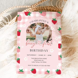 May include: Pink and white gingham patterned invitation with a photo of a baby girl in a white dress. The invitation says "Charlotte's Berry First Birthday" and includes the date, time, and location of the party. RSVP information is also included.