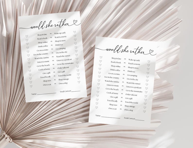 May include: Two printable "Would She Rather" game cards with a heart design. The cards feature a list of 16 questions with two choices each. The questions are about lifestyle preferences, such as sleeping in late or waking up early, reading a book or watching a film, and shopping online or shopping in a store.