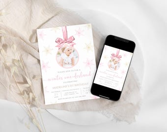 May include: A pink and white winter wonderland themed first birthday party invitation with a photo of a baby girl in a pink dress. The invitation features a pink and white snowflake ornament with a gold glitter background. The text on the invitation reads "Please join us for a winter one-derland celebrating Madeline's 1st Birthday".