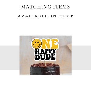 May include: A yellow and black cake topper with a smiley face and the text "ONE HAPPY DUDE" on a chocolate cake.