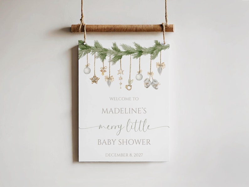 the merry little baby shower sign is shown hanging as decor against a wall to display. the photo shows the 16x20” printed sign option.