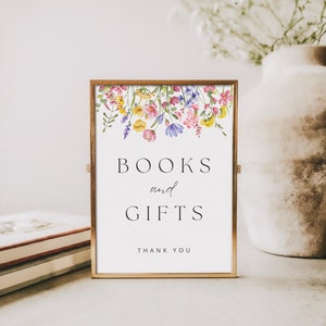 May include: A gold framed sign with a floral design at the top. The sign says "BOOKS and GIFTS" with the words "THANK YOU" at the bottom.