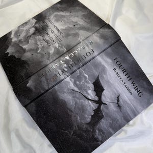 May include: A hardback book titled Fourth Wing by Rebecca Yarros with a black and white cover featuring a dragon silhouette flying through clouds and stars. The back cover includes the text: There's nowhere in existence you could go that I wouldn't find you. Violence.