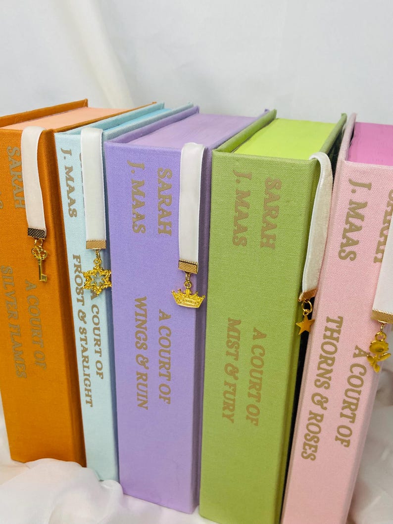 Pode incluir: Um conjunto de seis livros de capa dura com lombadas de cores combinando e marcadores de fita branca. Os livros s&atilde;o intitulados "A Court of Thorns & Roses", "A Court of Mist & Fury", "A Court of Wings & Ruin", "A Court of Frost & Starlight", "A Court of Silver Flames", e "A Court of ...".