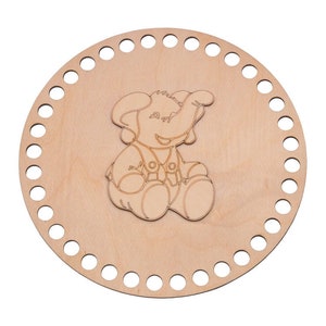 Op de afbeelding: Een ronde houten weefgetouw met een cirkelvormig ontwerp van een olifant in het midden. Het weefgetouw heeft gaten rond de rand om garen in te rijgen.