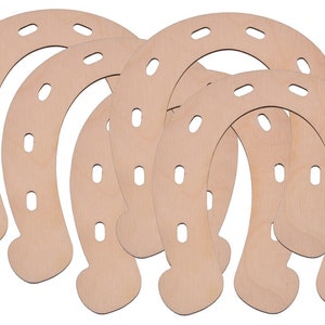 Op de afbeelding: Vijf onafgewerkte houten hoefijzers, elk met zes gaten rond de rand.