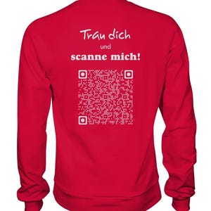 Könnte beinhalten: Roter Langarm-Pullover mit weißem Text "Trau dich und scanne mich!" und einem weißen QR-Code.