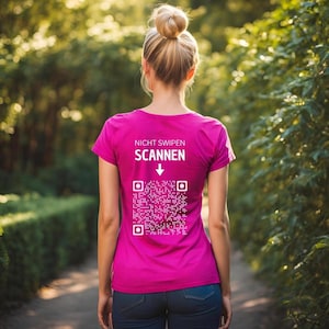 Könnte beinhalten: Ein pinkfarbenes T-Shirt mit dem Text "Nicht Swipen Scannen" und einem nach unten zeigenden Pfeil, der auf einen QR-Code zeigt.