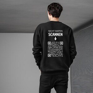 Könnte beinhalten: Schwarzer Pullover mit weißem Text "Nicht Swipen Scannen" und einem QR-Code mit einem nach unten zeigenden Pfeil.