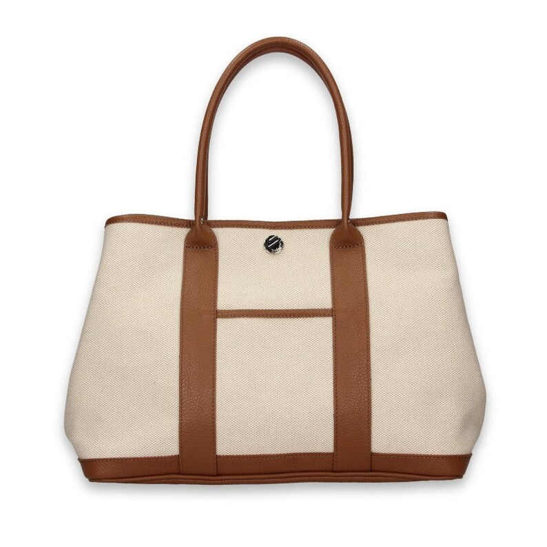 Pu&ograve; includere: Borsa tote color crema con finiture e manici in pelle marrone. La borsa ha una tasca frontale e una chiusura in metallo argentato. I manici sono arcuati e la borsa ha una forma rettangolare.