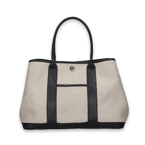 Pu&ograve; includere: Una borsa tote beige con finiture e manici in pelle nera. La borsa presenta una tasca frontale e una chiusura color argento. Il design della borsa &egrave; semplice ed elegante, adatta all'uso quotidiano.