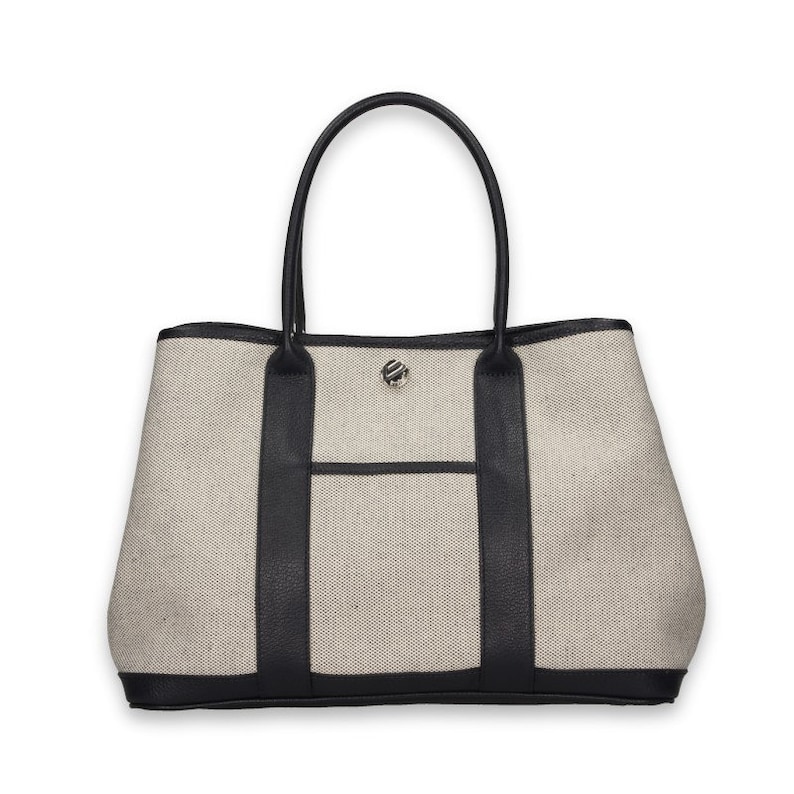 Pu&ograve; includere: Una borsa tote beige con finiture e manici in pelle nera. La borsa presenta una tasca frontale e una chiusura color argento. Il design della borsa &egrave; semplice ed elegante, adatta all'uso quotidiano.
