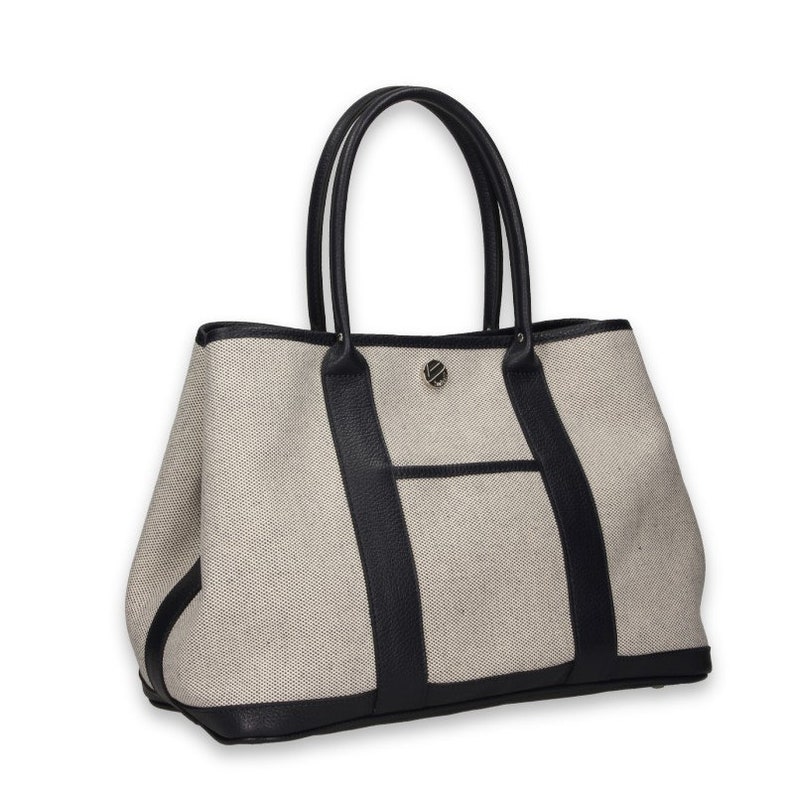 Pu&ograve; includere: Borsa tote beige con dettagli in pelle nera. La borsa presenta manici neri, base nera e finiture nere. Una piccola tasca &egrave; visibile sul davanti e un'emblema argentato &egrave; centrato sul davanti.