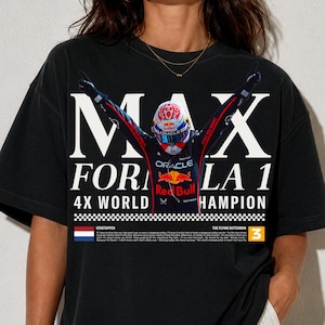 May include: A black short-sleeve t-shirt featuring a graphic of a Formula 1 driver in a racing suit with arms raised. The text reads MAX FORMULA 1 4X WORLD CHAMPION, with a Dutch flag, the number 3, and additional small printed text below.