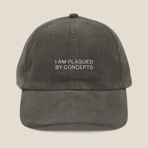 May include: A dark green corduroy baseball cap with white embroidery that reads "I AM PLAGUED BY CONCEPTS".