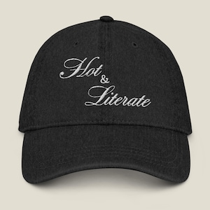 Op de afbeelding: Zwarte baseballcap met de geborduurde tekst "Hot & Literate" in wit script. De cap heeft een gebogen klep en een knoop bovenop. Een modieus accessoire voor dagelijks gebruik.