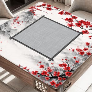 May include: A wooden square table with a decorative top featuring a gray center and a white background with a mountain scene. Red cherry blossoms adorn the edges, creating a striking contrast.
