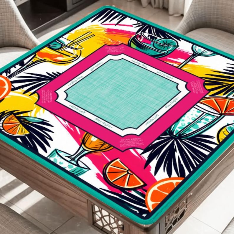 May include: A square table mat with a vibrant tropical design. The mat features colorful illustrations of cocktails, orange slices, and palm leaves. The central area is a light blue rectangle framed by a pink border with text. The mat is trimmed with a teal border.