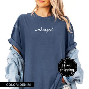 May include: A denim blue t-shirt with the word "unhinged" written in white script on the front.