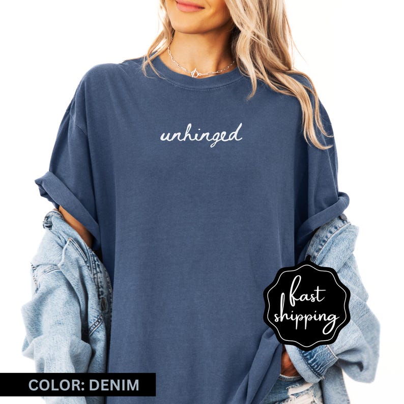 May include: A denim blue t-shirt with the word "unhinged" written in white script on the front.