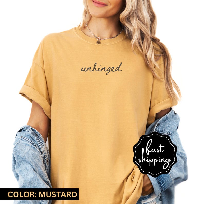 May include: A mustard yellow t-shirt with the word "unhinged" written in black cursive on the front.