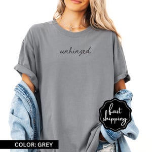 May include: A grey t-shirt with the text "unhinged" printed on the front in black.