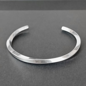 May include: A silver metal bangle bracelet with a twisted design.