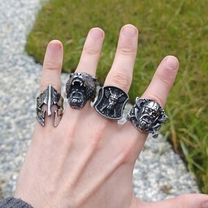 Pu&ograve; includere: Quattro anelli d'argento con diversi design. Un anello presenta una testa d'orso, un altro uno scudo con una testa vichinga, un altro un elmo e l'ultimo una testa vichinga con una spada.