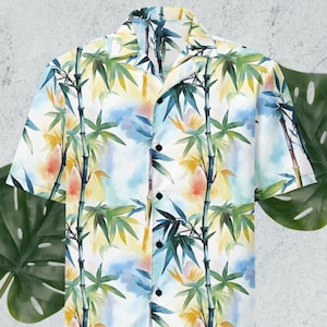 May include: A white short-sleeved button-down shirt with a watercolor print of bamboo stalks and leaves in shades of green, yellow, and orange.