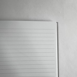 May include: A white lined notebook with a gray spine.
