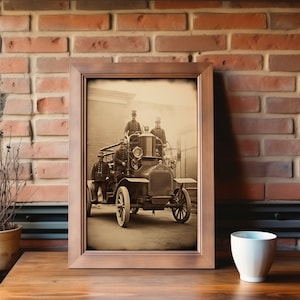 May include: A vintage black and white photograph of a fire engine with three firefighters in uniform standing on the back of the vehicle. The photo is framed in a brown wooden frame.