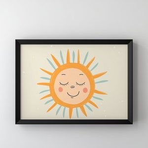 May include: A framed print of a cartoon sun with a smiling face and closed eyes. The sun is yellow with blue rays and is set against a light beige background.