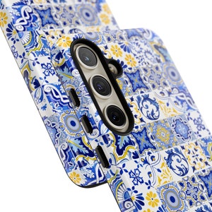 Peut inclure: Une coque de téléphone avec un motif de carreaux bleus et blancs. La coque a un découpage pour l'appareil photo avec trois objectifs.