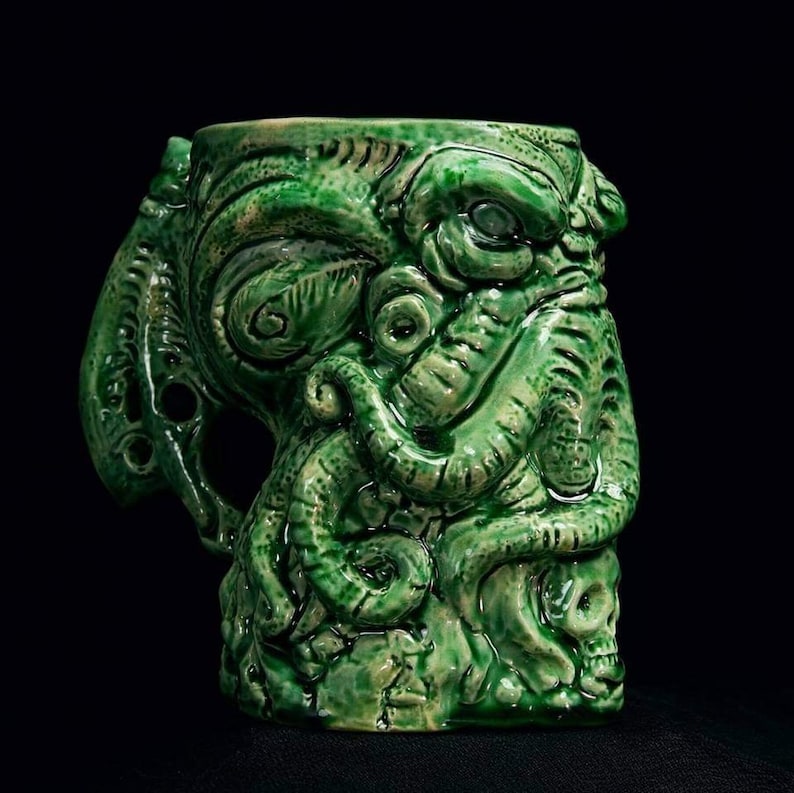 May include: Green ceramic mug shaped like a tentacled monster with a skull at the base.