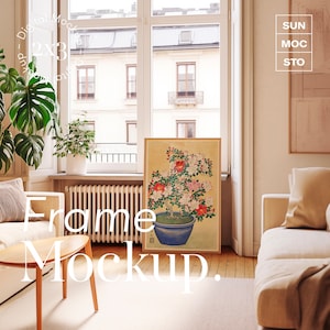May include: A framed art print featuring a botanical illustration of a flowering bonsai tree in a blue pot. The artwork has red and pink flowers with green foliage. The frame is a light wood color. The image is in a living room setting.