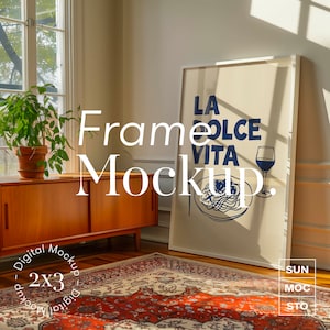 May include: A white frame mockup with a beige mount and a blue and white print that says "La Dolce Vita" with a plate of spaghetti and a glass of wine. The frame is on a red and cream patterned rug in a room with a wooden cabinet and a plant.