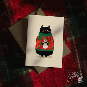 May include: A greeting card with a cartoon black cat wearing a red Christmas sweater and green scarf. The cat is holding a snowman cup. The card is on a red and green plaid background. The card is a festive design.