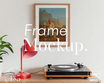 May include: A framed picture of a man sitting on a bench in a landscape setting. The frame is on a wooden shelf with a red lamp, a record player, and a record on the shelf. The text "Frame Mockup" is written in white on the wall.