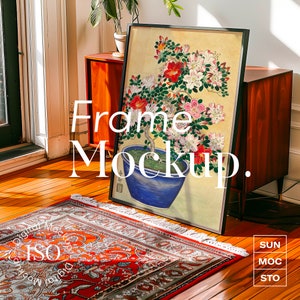 Può includere: Un'immagine incorniciata in nero con un dipinto di un bonsai con fiori rosa in un vaso blu. L'immagine è appoggiata su un mobile in legno e un tappeto con un motivo rosso e arancione.