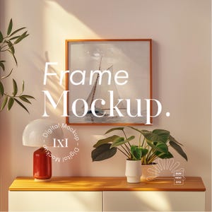 May include: A framed artwork featuring a sailboat scene hangs above a wooden cabinet. A red and white lamp and potted plants are on the cabinet. The image includes the text "Frame Mockup" and "Digital Mockup - IXI".