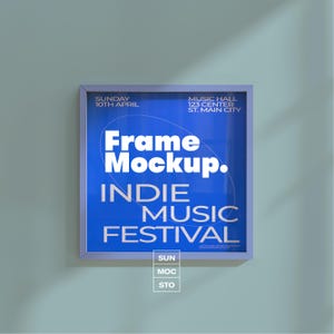 Könnte beinhalten: Quadratische Rahmenattrappe mit blauem Hintergrund mit dem Text "Frame Mockup. INDIE MUSIC FESTIVAL". Zusätzlicher Text enthält "SUNDAY 10TH APRIL" und "MUSIC HALL 123 CENTER ST. MAIN CITY."