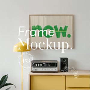 May include: A framed print with the word "now" in green letters on a white background. The frame is on a wall above a yellow dresser with a vintage stereo and a yellow lamp.