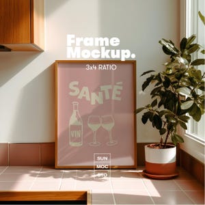 May include: A framed pink poster with the word "SANTE" in white, along with a wine bottle and two wine glasses. The frame is gold-colored. The text "Frame Mockup. 3x4 RATIO" is at the top. The bottom of the poster has the text "SUN MOC STO".