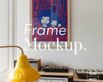 May include: A framed poster with a vintage design featuring a band with the text "POP MUSIC FESTIVAL" and "Jimi Hendrix" in red and blue lettering. The poster is hanging on a white wall above a wooden cabinet with a yellow lamp, a stereo, and a keyboard.
