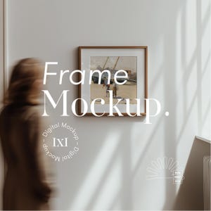 May include: A brown wooden frame with a white mat and a picture of a beach scene with people in the distance. The text "Frame Mockup." is written in white letters on a white wall.