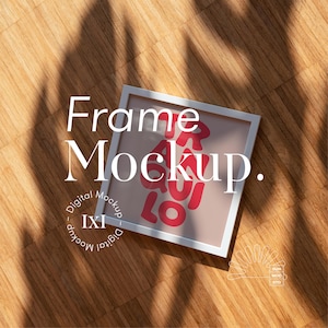 May include: White frame mockup with a pink background and red text that says "Frame Mockup." The frame is on a wooden surface with shadows from sunlight.