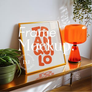 May include: A gold frame mockup with a white background and orange text that says "Frame Mockup". The frame is sitting on a gold table with a lamp and a plant.