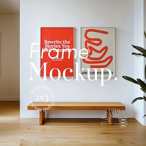 May include: Two framed posters hanging on a white wall. The poster on the left has a red background with white text that reads "Rewrite the Stories You Tell Yourself". The poster on the right has a cream background with a red abstract design and the text "Dare to Dream Imperfectly".